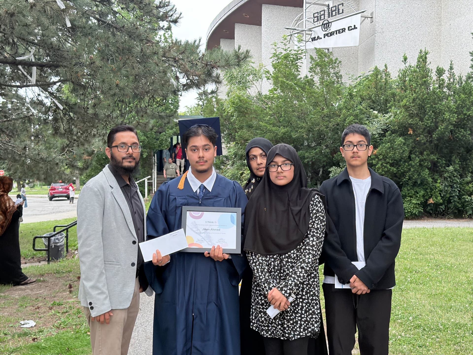 Jihan in graduation gown with family outside the school