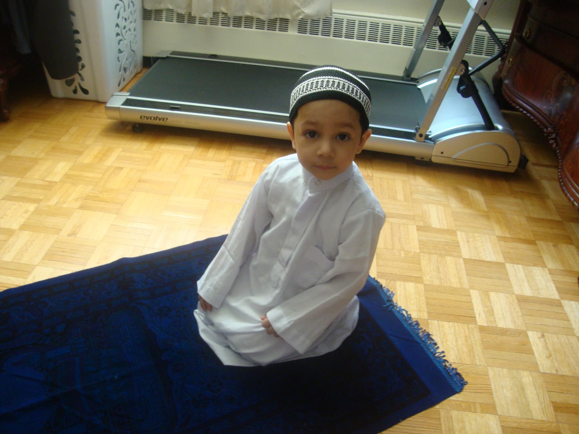 Baby Jihan sitting on a prayer rug